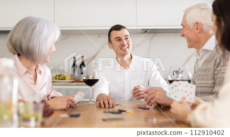 Man playing poker game with parents and wife in kitchen Man playing poker game with parents and wife in kitchen 112910402