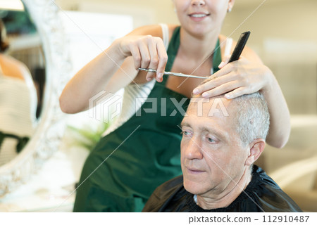 Senior gray-haired male client getting haircut in hairdressing salon 112910487