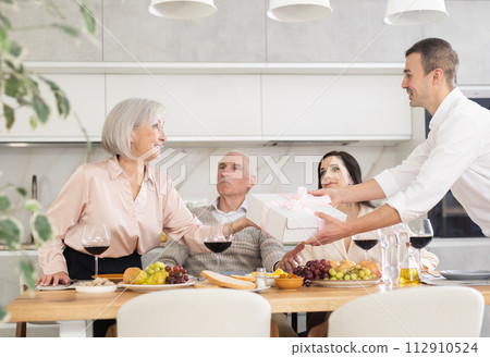 Birthday senior woman accepts valuable gift from adult son during family feast 112910524