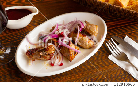 Grilled pork meat shashlik with sliced onion 112910669