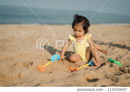 happy toddler baby girl playing sand toy on sea beach 112910697