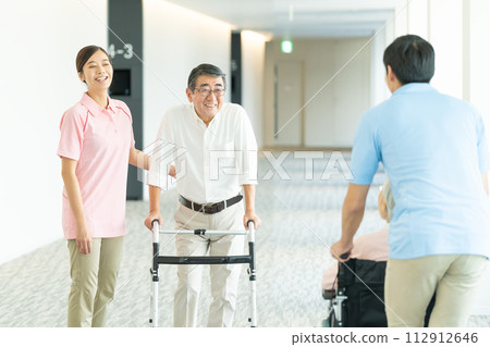 Elderly people in wheelchairs and young helpers who care 112912646