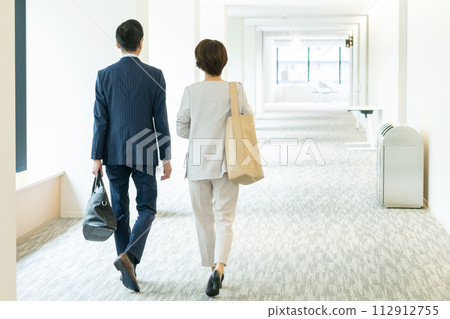 Rear view of a walking businessman and businesswoman 112912755