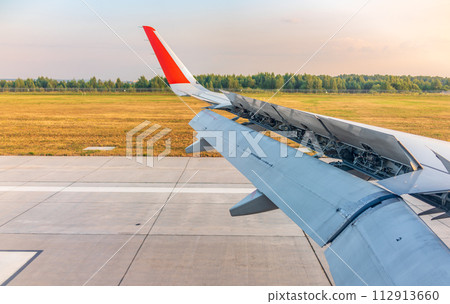 View of airplane wing, blue skies and green land during landing. Airplane window view. 112913660