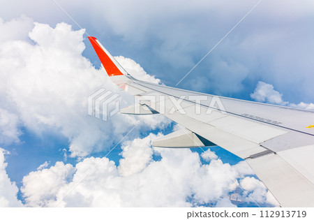 View from the airplane window at a beautiful cloudy sky and the airplane wing 112913719