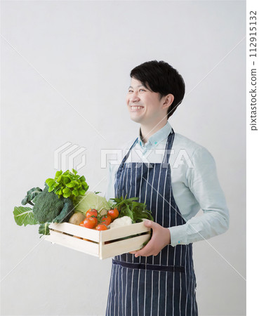 A man holding a box containing organic vegetables as ingredients A man holding a box containing organic vegetables as ingredients 112915132