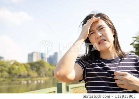 Tired asian woman with headache,dizziness,walking outdoor on sunny day,strong sunlight,hot weather,high temperature heat wave,harsh ultraviolet rays of sun in summer,Heat stroke,sweaty and thirsty Tired asian woman with headache,dizziness,walking outdoor on sunny day,strong sunlight,hot weather,high temperature heat wave,harsh ultraviolet rays of sun in summer,Heat stroke,sweaty and thirsty 112915905