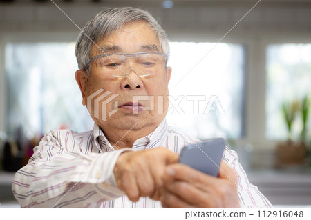 A senior Japanese man who has trouble operating a smartphone A senior Japanese man who has trouble operating a smartphone 112916048