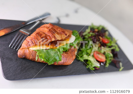 4K Breakfast Scene. A woman is eating a croissant with bacon and scrambled eggs at breakfast. High quality 4k footage 4K Breakfast Scene. A woman is eating a croissant with bacon and scrambled eggs at breakfast. High quality 4k footage 112916079