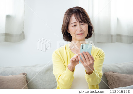 在客廳裡操作智能手機的女高管 在客廳裡操作智能手機的女高管 112916138