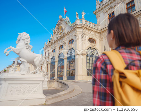 Female tourist traveling in Austria, capital city Vienna. summer female solo trip to Europe, happy young woman walking in park near Belvedere palace complex in Baroque style. 112916656