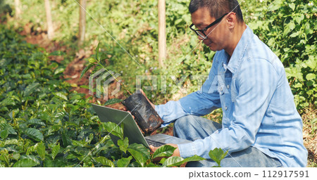 Smart farmer using laptop in eco green farm sustainable quality control. Close up Hand typing laptop computer quality control plant tree. Farmer hands using technology in eco Farmland biotechnology Smart farmer using laptop in eco green farm sustainable quality control. Close up Hand typing laptop computer quality control plant tree. Farmer hands using technology in eco Farmland biotechnology 112917591