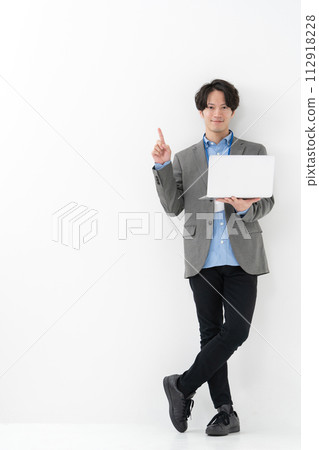 A man holding a laptop and pointing 112918228