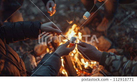 Hands of friends roasting marshmallows on the fire at campsite. Camping and food concept Hands of friends roasting marshmallows on the fire at campsite. Camping and food concept 112918771