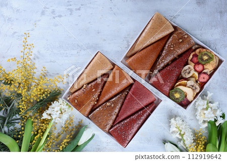 Fruit pastille. The pastille is rolled up in the form of a cone. Vegan sweets, dessert without sugar. Spring flowers. The concept of healthy eating. 112919642