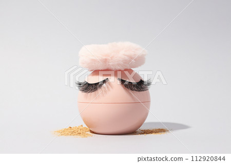 Face powder, with a puff for application, on a light background. 112920844