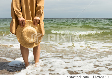 A girl in a dress walks on the beach in the summer. 112920905