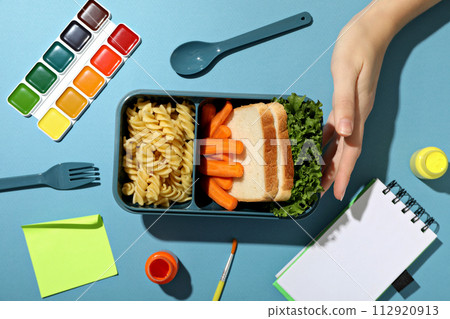 A blue lunchbox with food and drawing supplies A blue lunchbox with food and drawing supplies 112920913