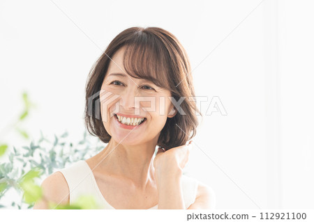 Middle-aged woman smiling with her hand in her hair Middle-aged woman smiling with her hand in her hair 112921100