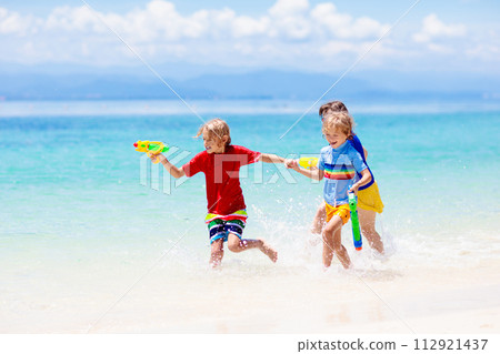 Child with toy water gun. Kids vacation beach fun. 112921437