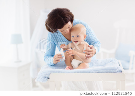 Mother changing diaper to baby boy Mother changing diaper to baby boy 112921840