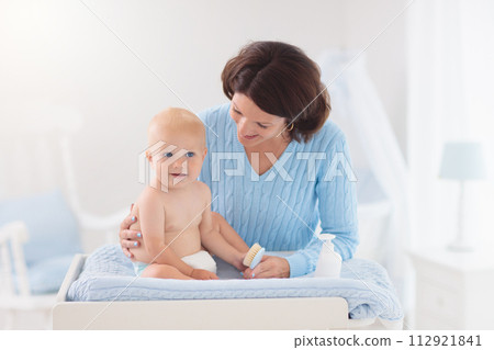 Mother changing diaper to baby boy Mother changing diaper to baby boy 112921841