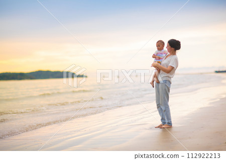Mother and baby on tropical beach at sunset. Mother and baby on tropical beach at sunset. 112922213