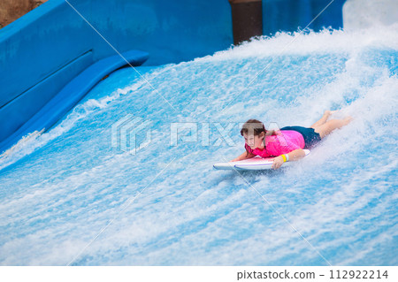 Child surfing in wave pool. Surfer training. Child surfing in wave pool. Surfer training. 112922214