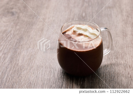 Hot chocolate served in a glass mug with cocoa and fresh cream Hot chocolate served in a glass mug with cocoa and fresh cream 112922662