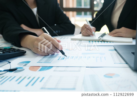 Two people are sitting at a table with a lot of papers and a laptop 112922699