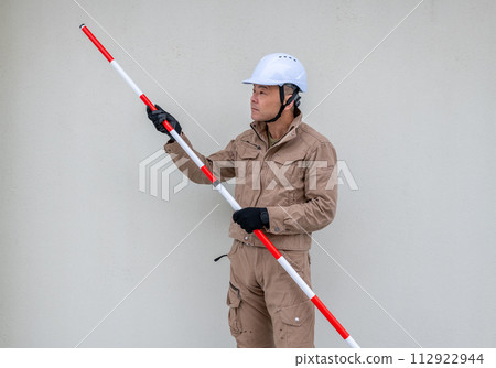 Field worker checking the length of a surveying pole Field worker checking the length of a surveying pole 112922944