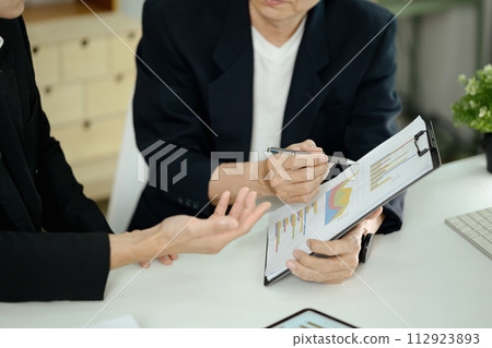 Cropped shot businesspeople analyzing financial statistic documents at office desk Cropped shot businesspeople analyzing financial statistic documents at office desk 112923893