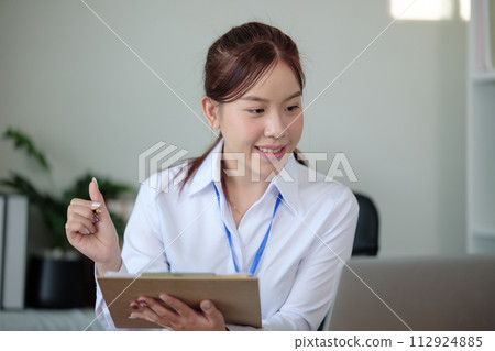 Portrait of beautiful asian young Business woman working audit and calculating expense annual financial report balance sheet statement,doing finance making notes on paper graph data checking document. 112924885