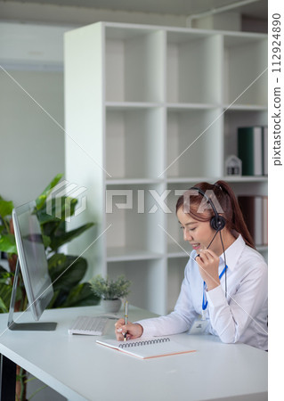 Portrait of happy smiling female customer support phone operator at workplace. Asian Portrait of happy smiling female customer support phone operator at workplace. Asian 112924890
