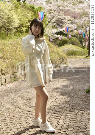 Young woman posing in a park with cherry blossoms blooming 112925155