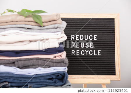 Black letter box and stack of folded clothes, reduce,reuse,recycle quote Black letter box and stack of folded clothes, reduce,reuse,recycle quote 112925401