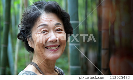 Radiant elderly woman smiling in bamboo forest Radiant elderly woman smiling in bamboo forest 112925483