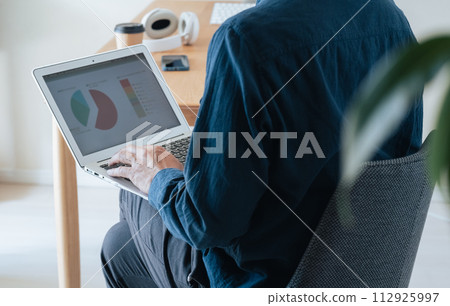 Middle-aged man operating a computer at home 112925997