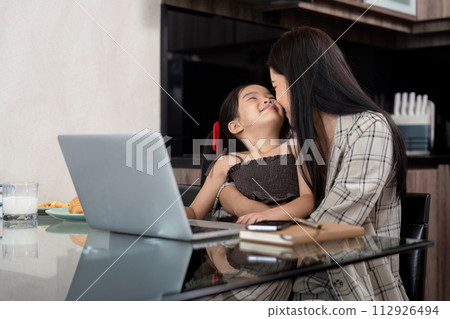 Business woman or mom working with her little daughter at a laptop. Freelance, work from home 112926494