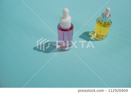 Face oil glass bottles on blue background. Summer skincare aesthetic on a tropical beach holiday 112926809