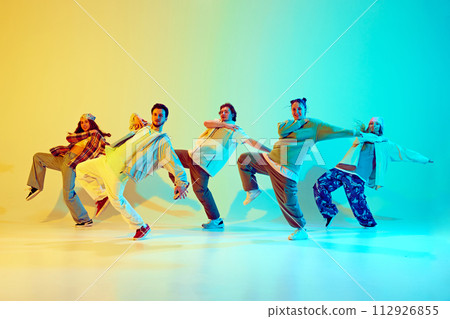 Artistic five dancers, young man and woman in motion, dancing against gradient green yellow background in neon light. 112926855