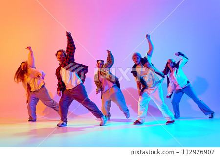 Synchronized movements. Group of young people dancing contemp against gradient studio background in neon light 112926902