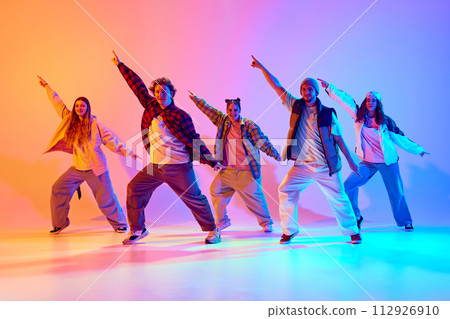 Dynamic poses in dancing. Young people, friends performing hip hop against gradient studio background in neon light 112926910