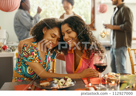 Smiling friends hugging and enjoy time spent together sitting at festive table during home party 112927000