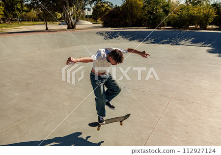 Active young man riding skateboard in skate park on sunny day. Extreme sport concept 112927124