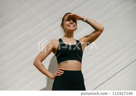 Female athlete in sportswear have a rest after morning jogging outside and looks away Female athlete in sportswear have a rest after morning jogging outside and looks away 112927186