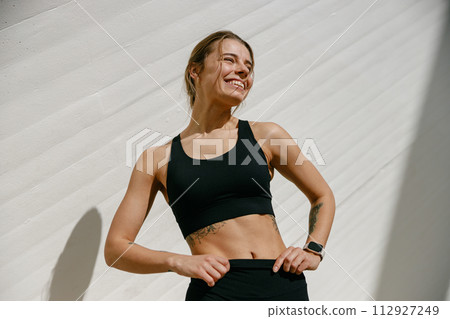 Young female athlete in sportswear have a rest after morning jogging outside and looks away Young female athlete in sportswear have a rest after morning jogging outside and looks away 112927249