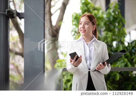 Asian business woman beautiful with smart phone and document file, asian woman with smartphone walking go to work. Preparation for the working day Asian business woman beautiful with smart phone and document file, asian woman with smartphone walking go to work. Preparation for the working day 112928149