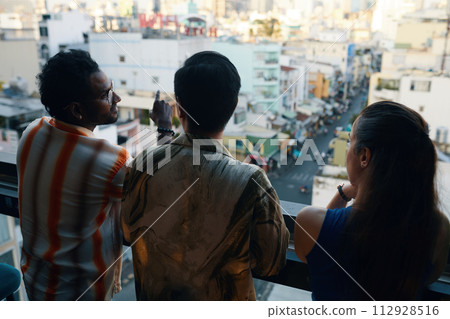 Group of people standing on balcony and looking at busy city, view from the back 112928516