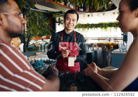 Smiling waiter taking food order in restaurant Smiling waiter taking food order in restaurant 112928582